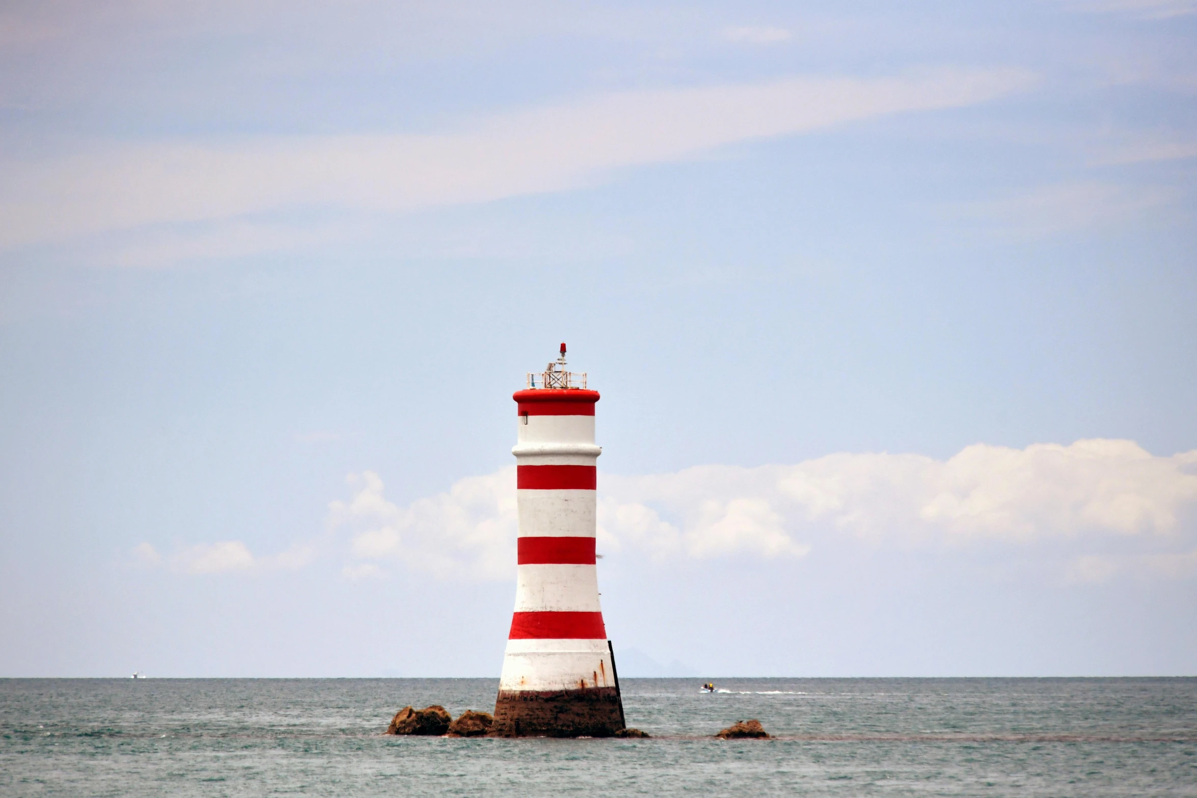 there is a red and white lighthouse standing in the middle of the ocean