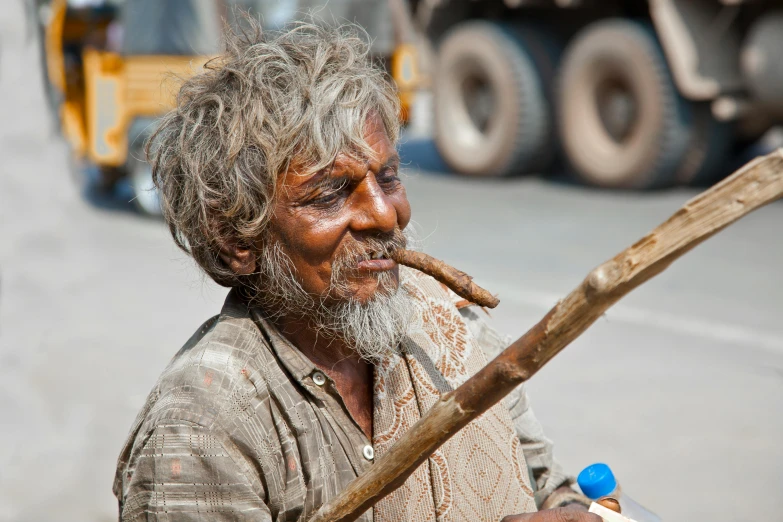 the man is smoking a cigarette with a long stick