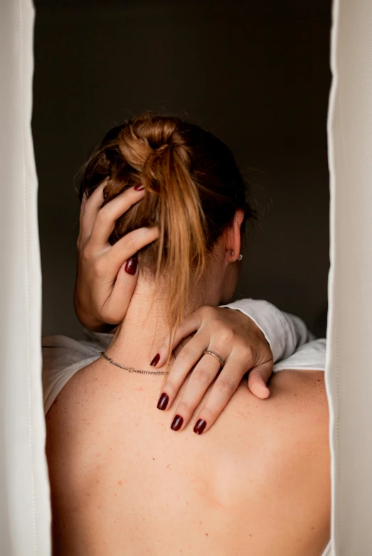 a person with their hand on their head looking through the hole in a curtain