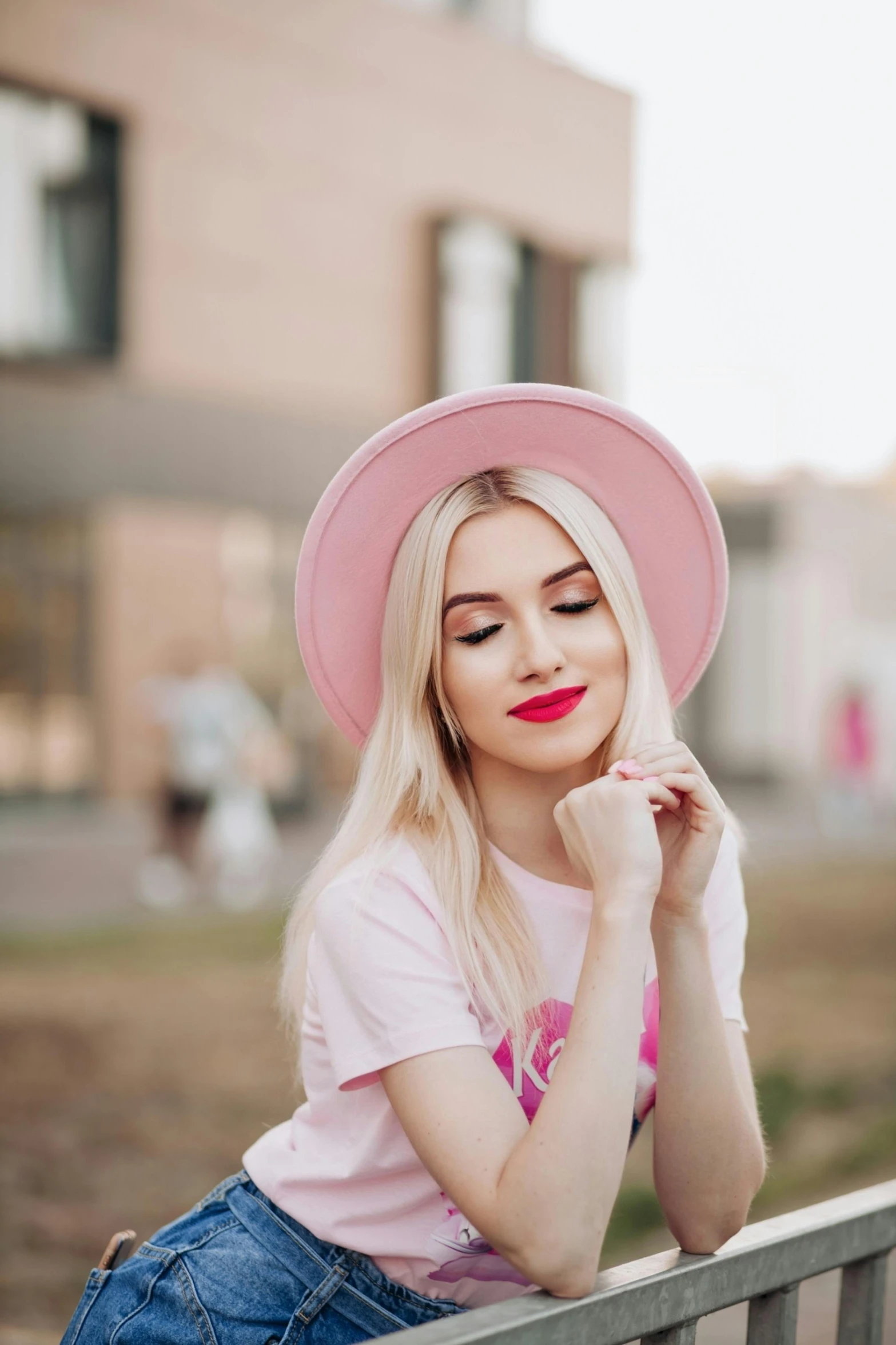 a blonde girl with a pink hat sitting on a bench