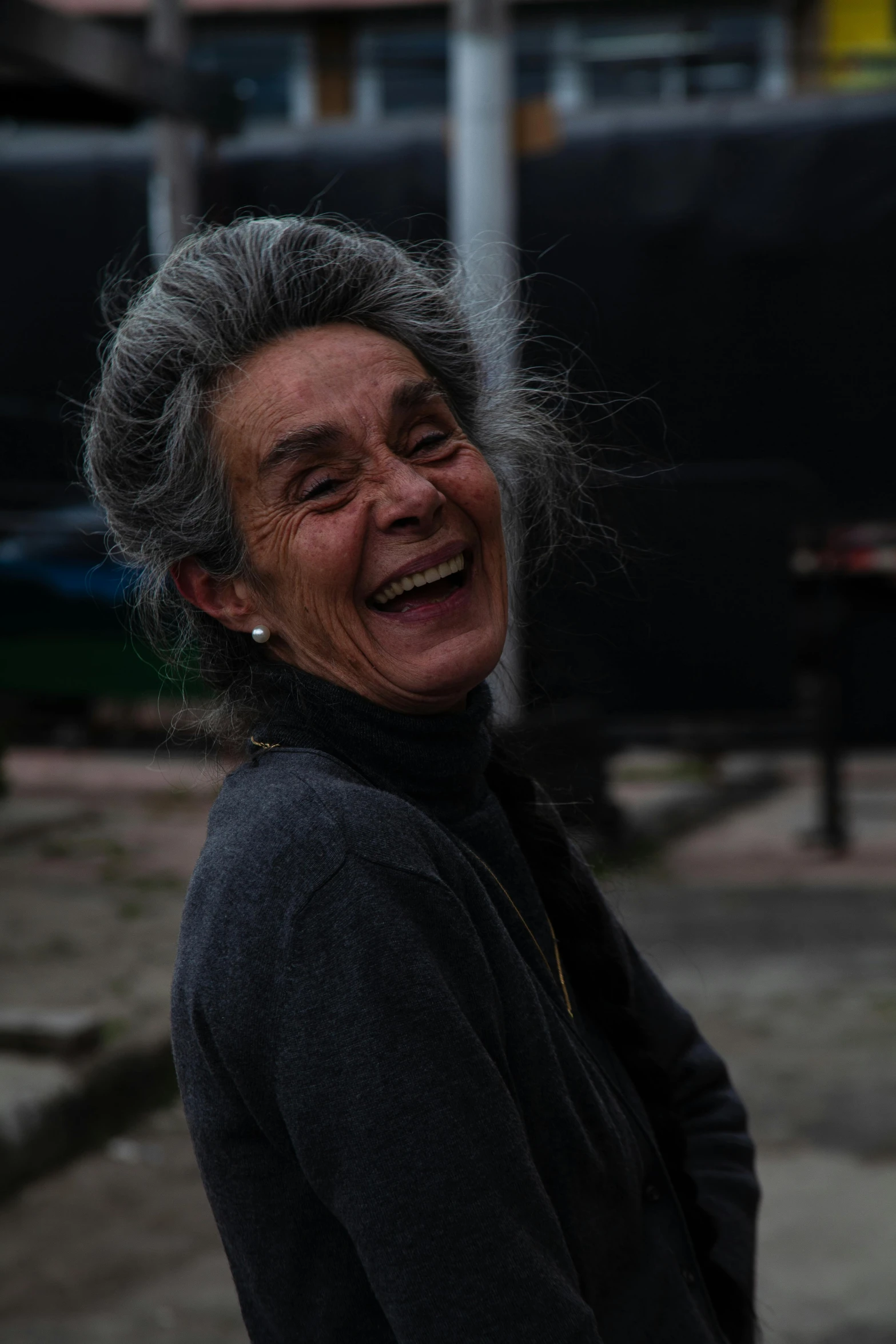 an old woman laughing for the camera, outdoors