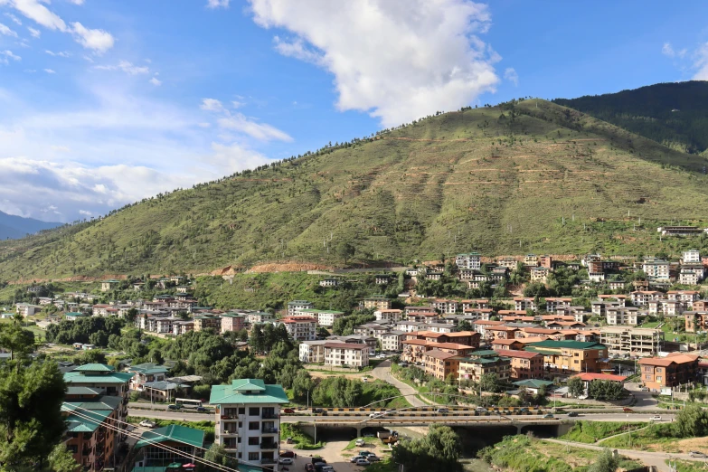 a large, brown village with green roofs is perched on the mountain side