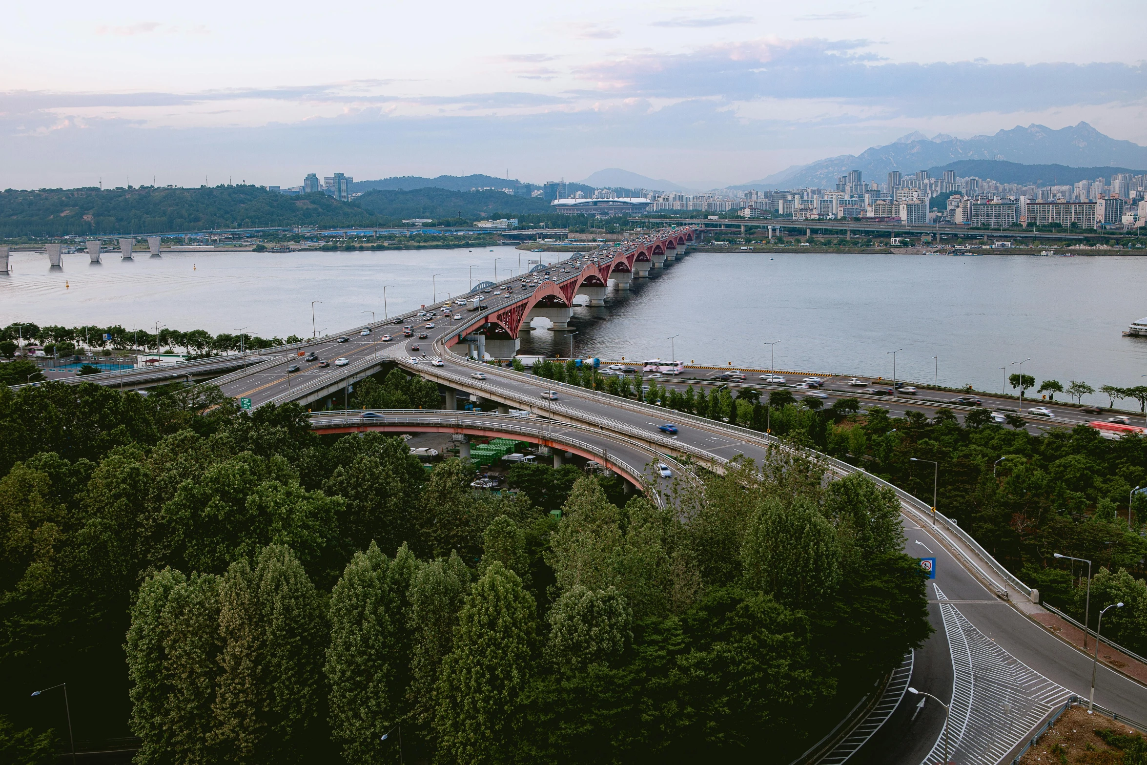 two lanes of traffic near a harbor with mountains in the distance