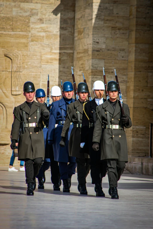 men in uniforms marching down a street while people watch