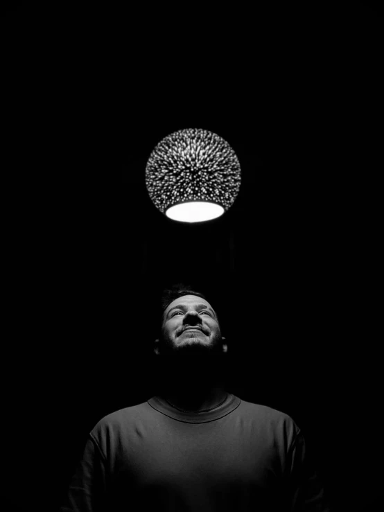 a man standing in the dark with his head under a light