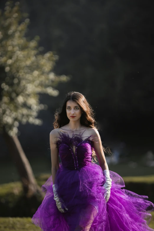 a woman in purple dress walking across grass