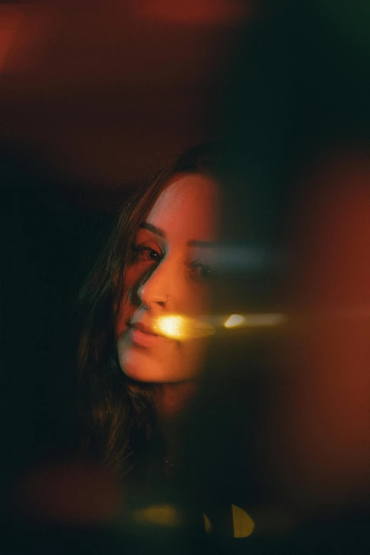 a young woman's profile as she sits in a dark room