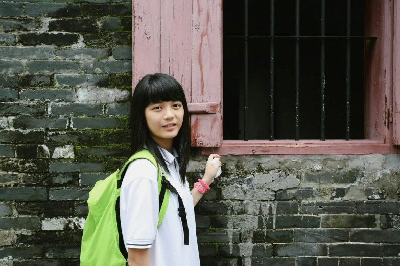 the girl is standing by the window posing for the camera