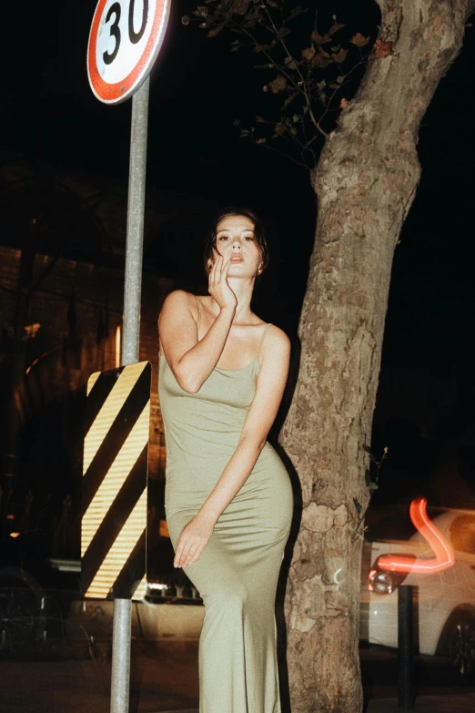 a woman standing on the sidewalk next to a sign