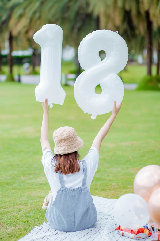 an image of a woman holding up balloons to the number 18