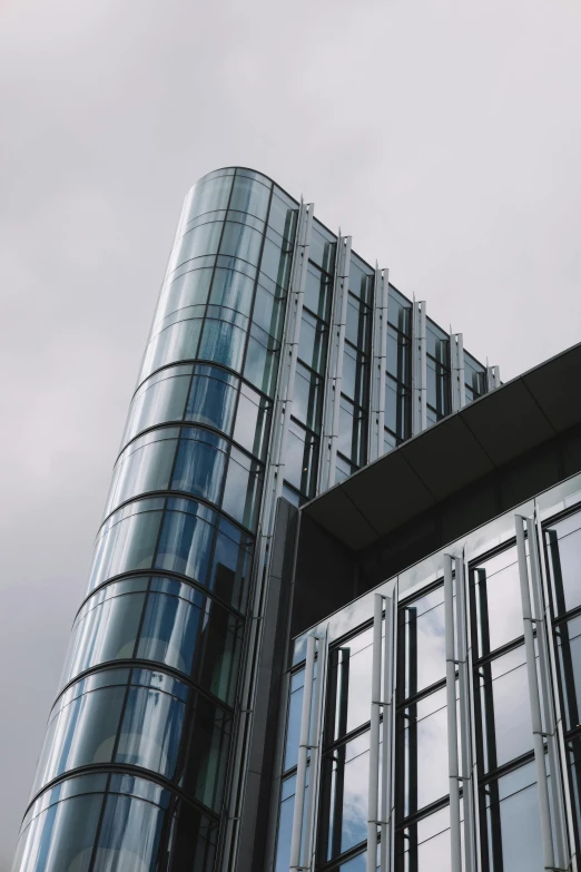 two glass buildings are against a cloudy sky