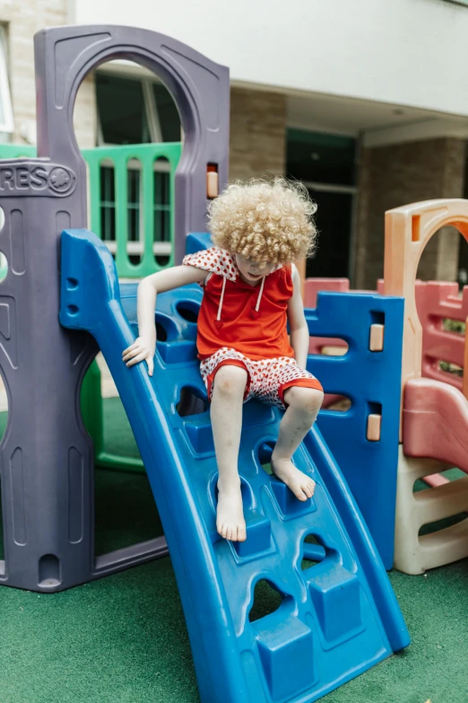 a little girl sitting on top of a slide