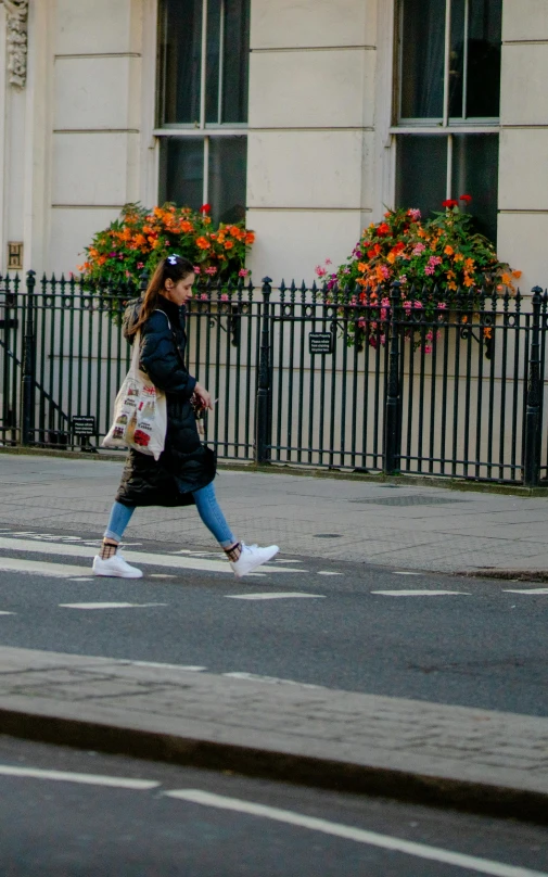 a woman crossing a street while holding a bag