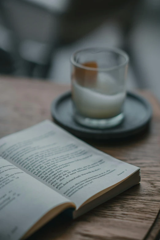 an open book sits next to a cup of coffee on a table