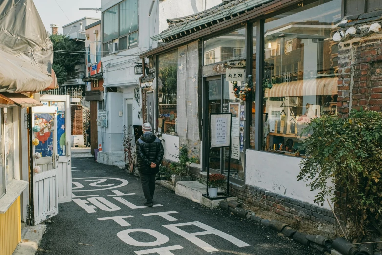 an empty street with storefronts with one person walking down it