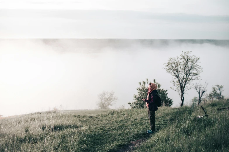 a person walking up a hill near the ocean on a foggy day