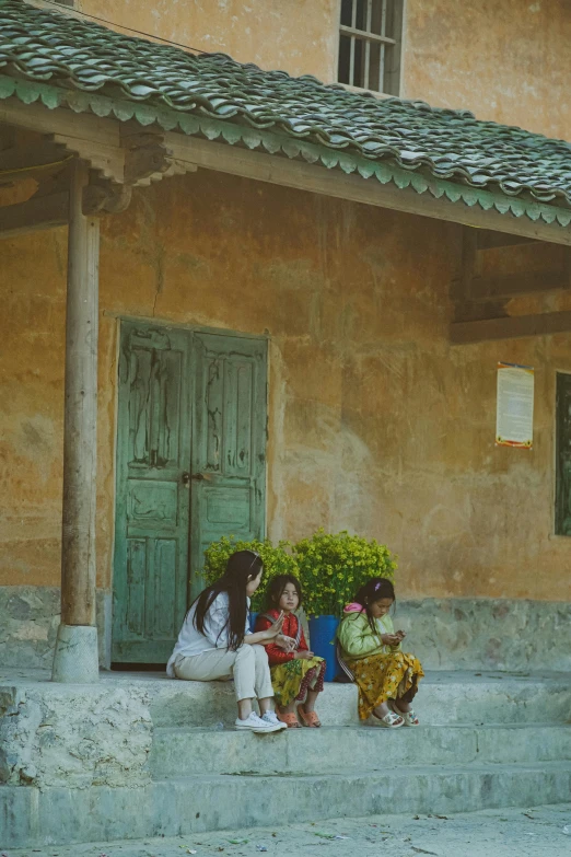 three girls sitting on the steps next to the door