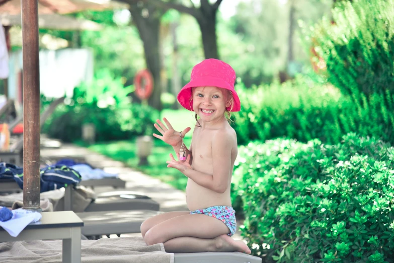 a young child with pink hat sitting on sand