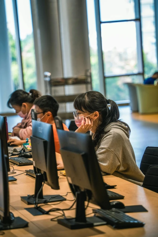 a woman works at desk with multiple monitors