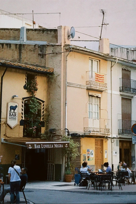 a large group of people sitting around tables outside of a building