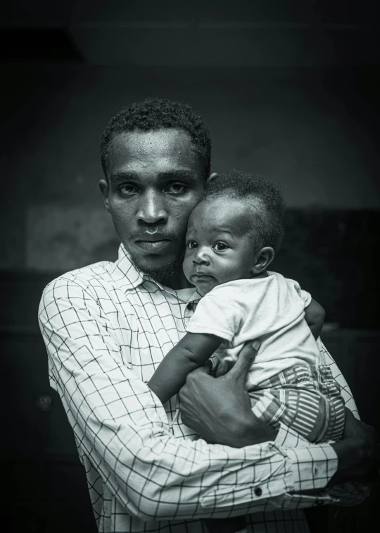 man holding his baby while standing next to him