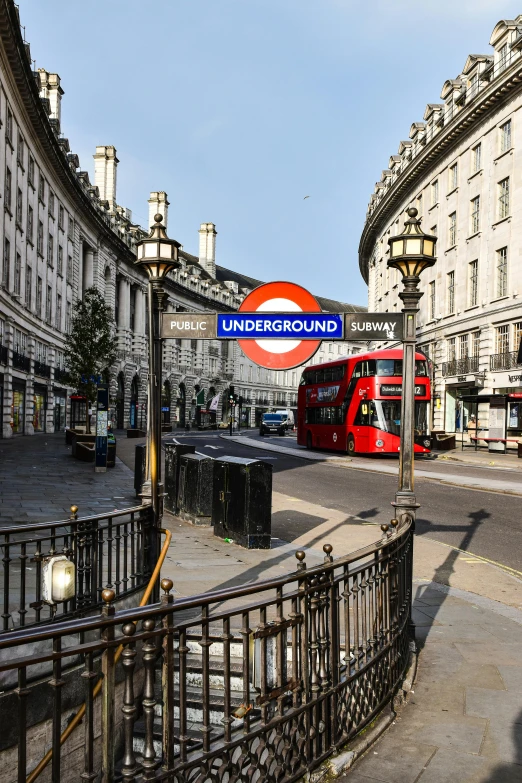 a red double decker bus driving past tall buildings