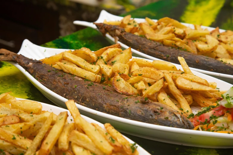 many plates with french fries and steak with green onions on them