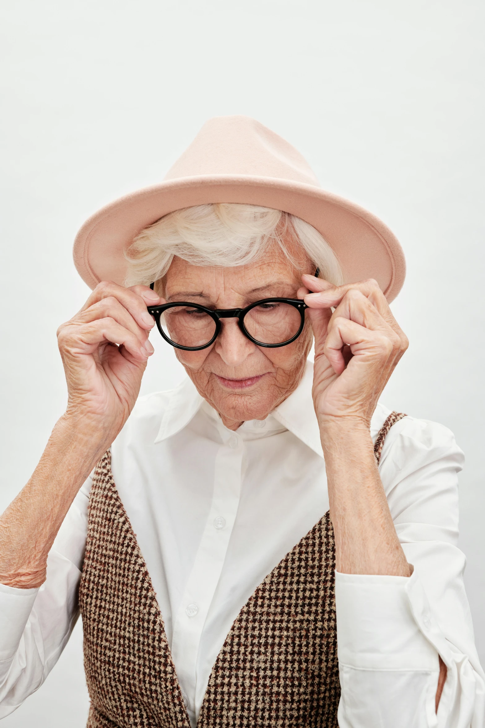 an old woman wearing a hat holding glasses