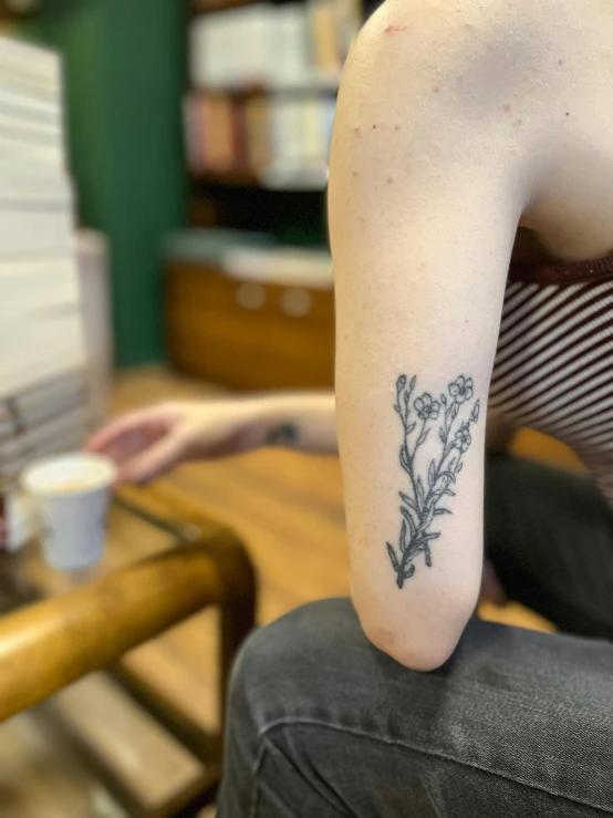 a close up of a person with a flower tattooed on their arm