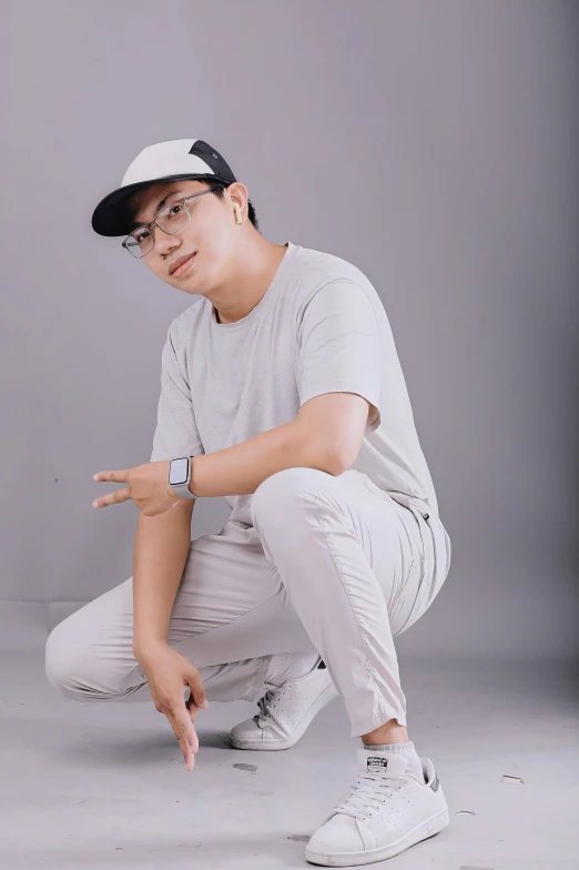 young man dressed in a baseball cap and white pants posing for a po