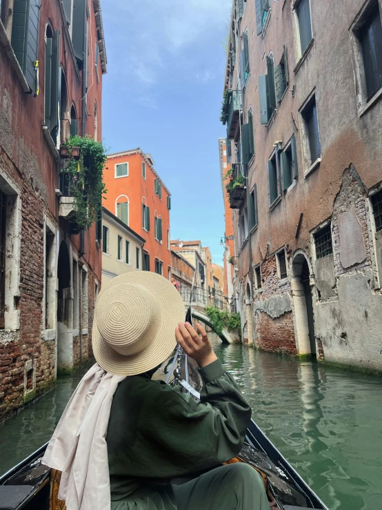 a woman riding down a canal using a cell phone