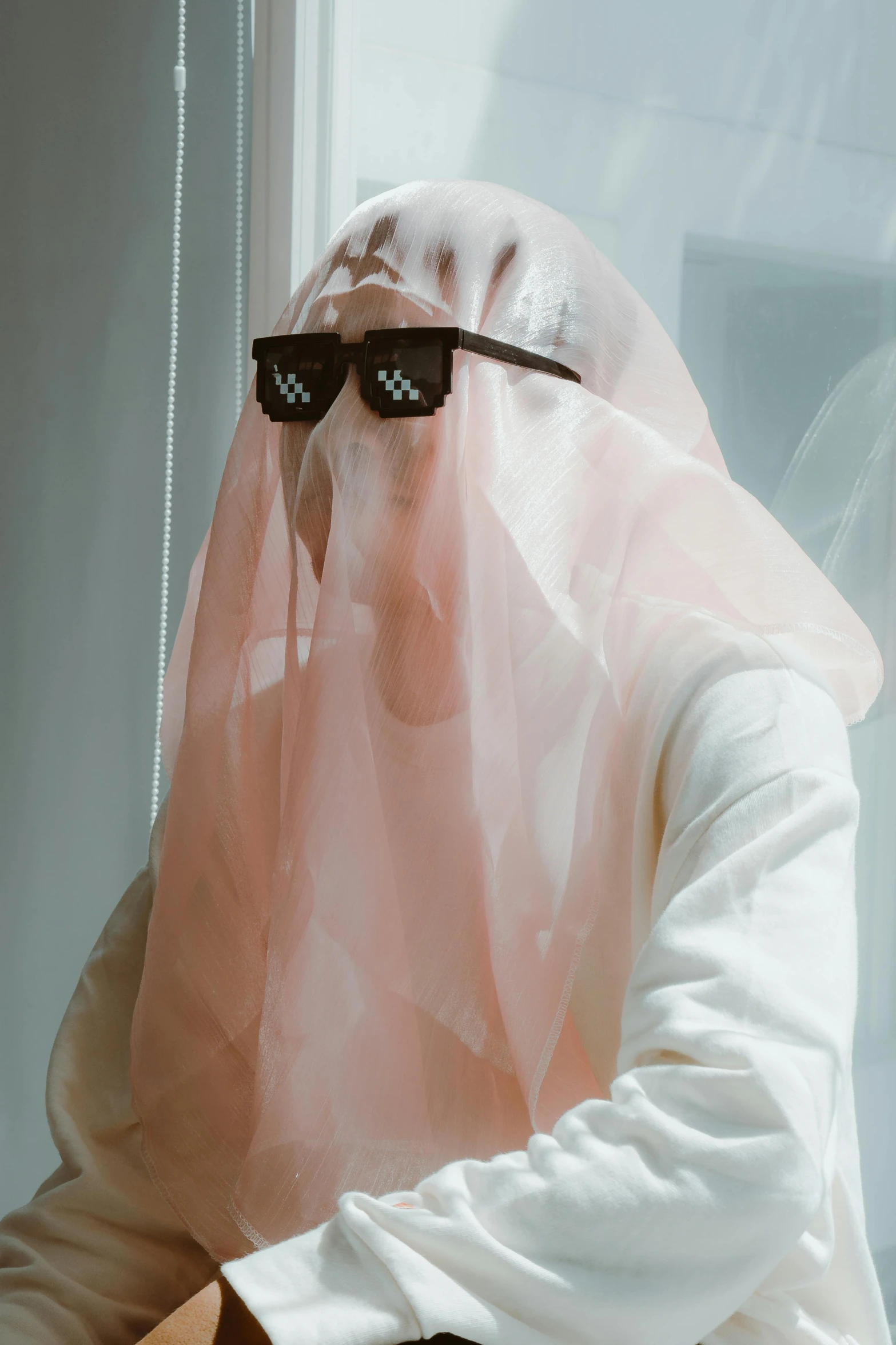 a person in glasses and a pink cloth covering him