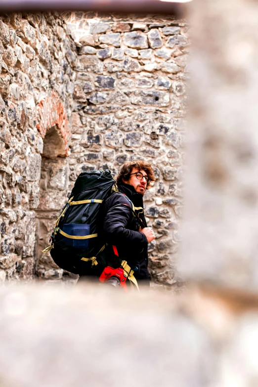 a man walking in front of an old brick wall