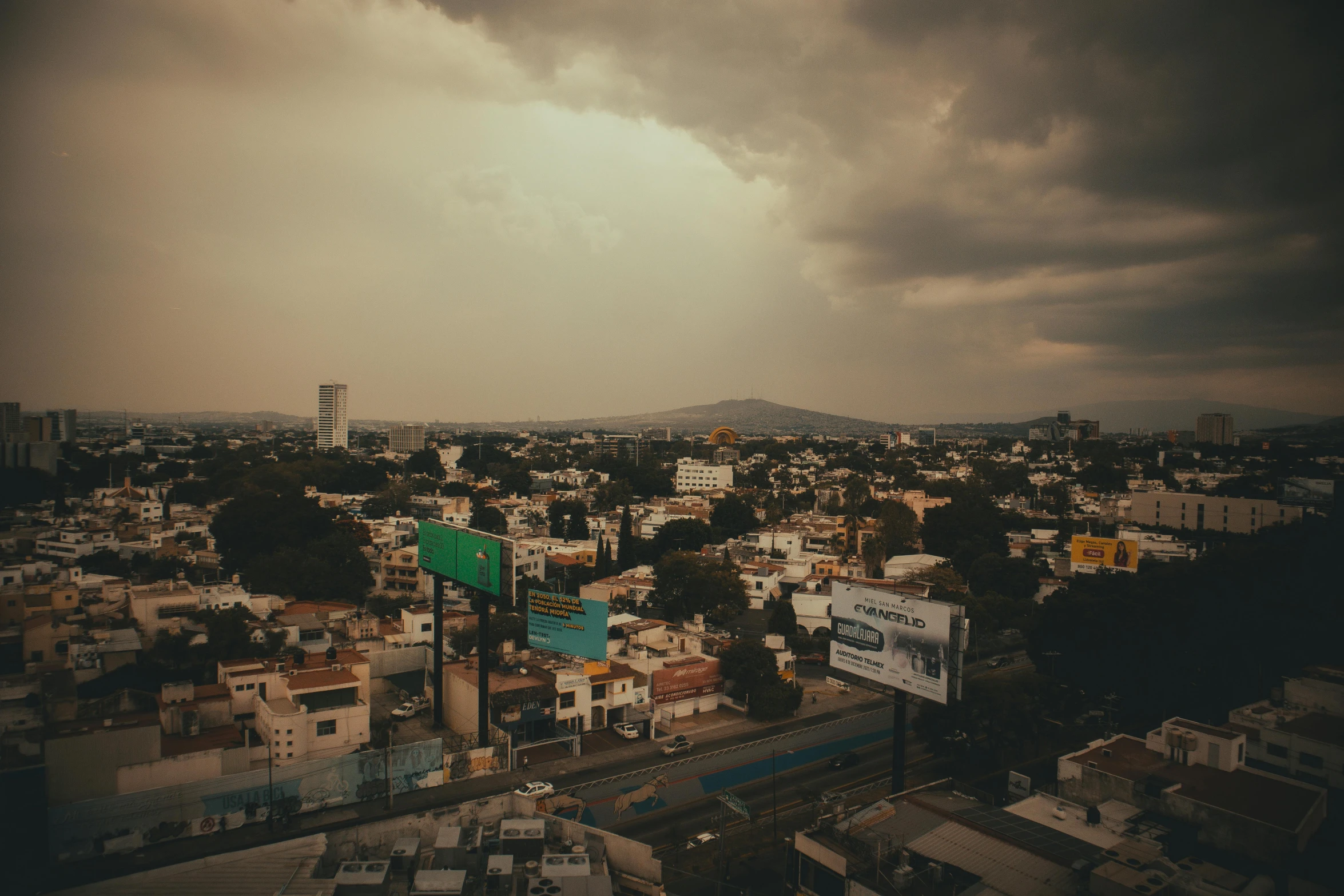 a cloudy view of city below and green street sign