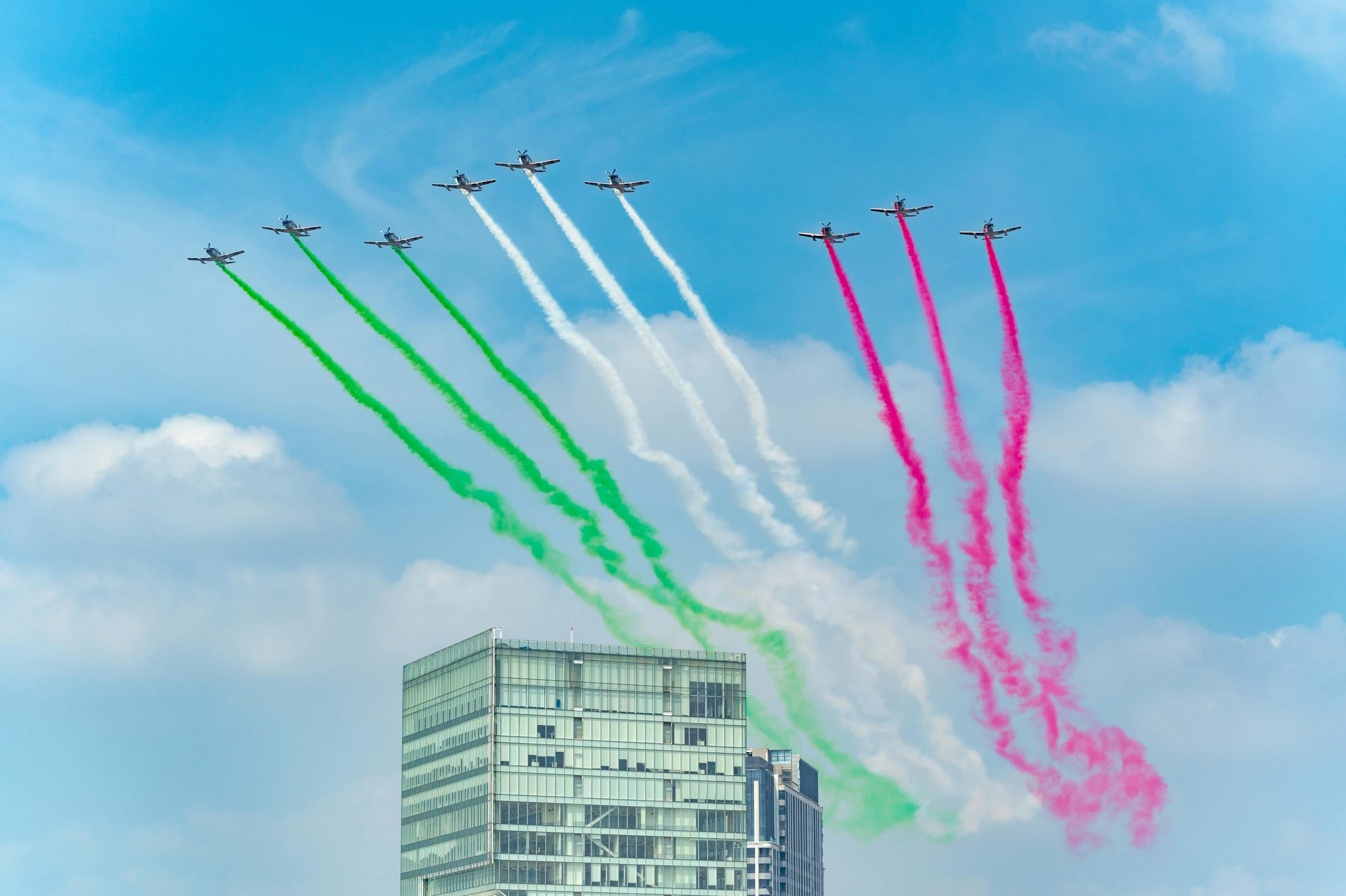 four jets fly through the air with colorful smoke trail