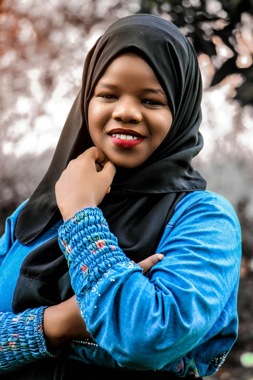 young woman in blue jacket with her hand under her chin