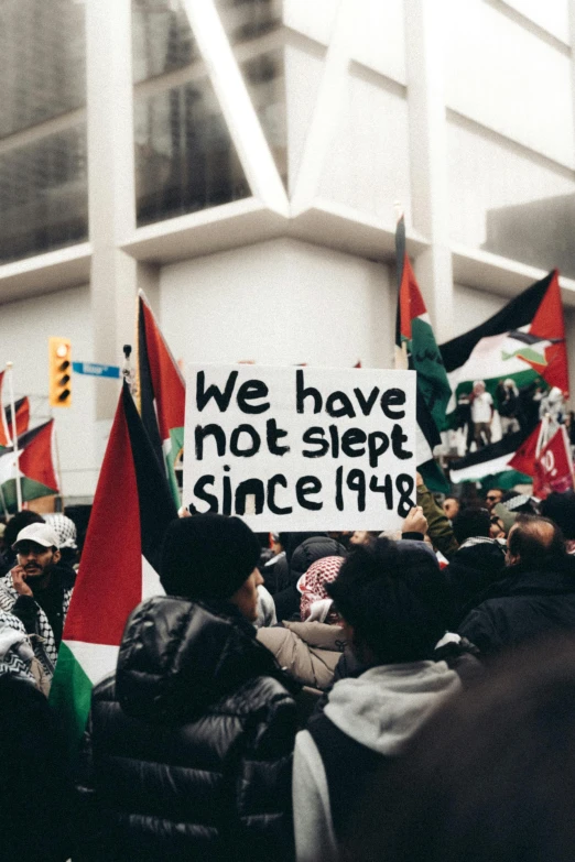 many people are holding signs in front of a building