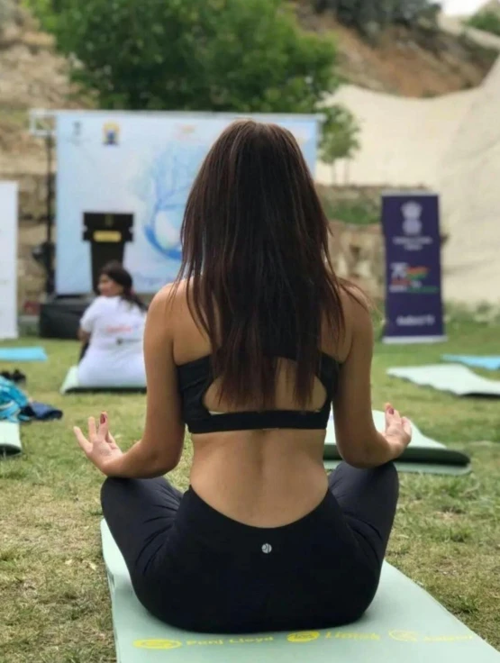 a girl sitting on a yoga mat in a park