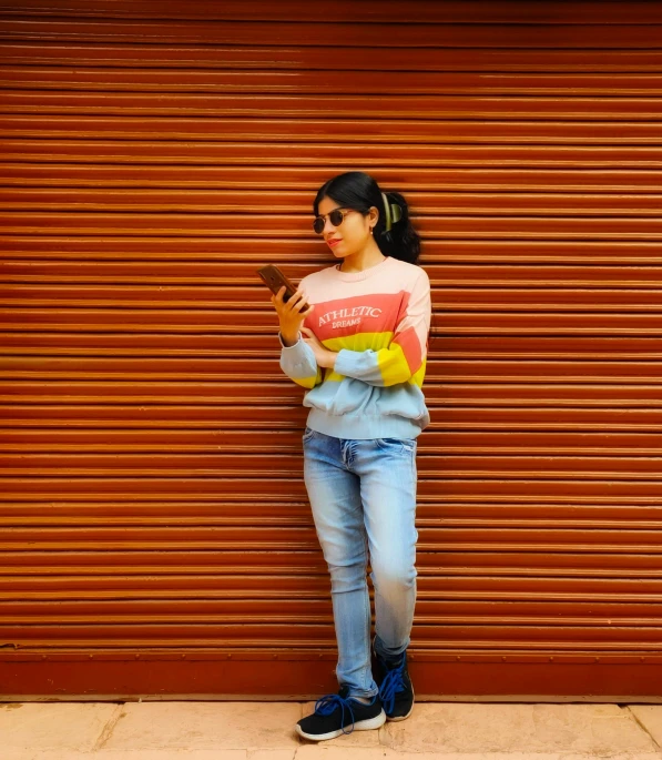 a girl in striped sweater standing against a door with her hand up to her chest