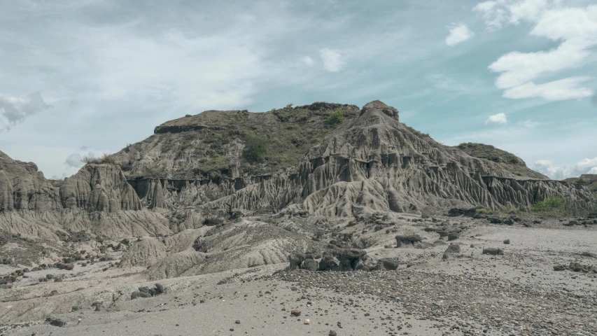 a large rock formation with small shrubs and sp grass