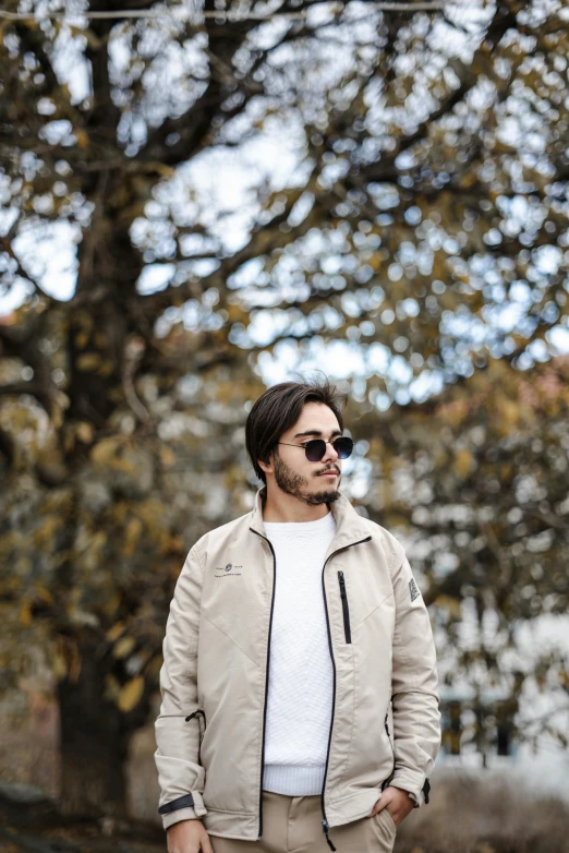 a man standing next to trees wearing sunglasses