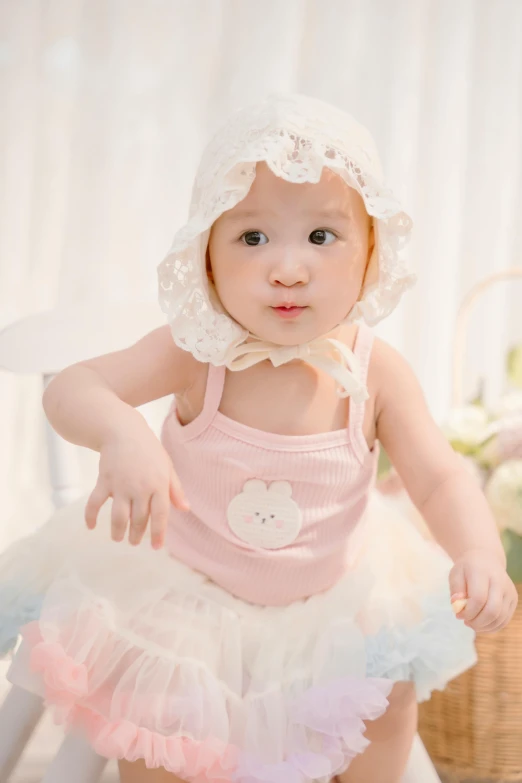 a young child in a pink dress and a white bonnet