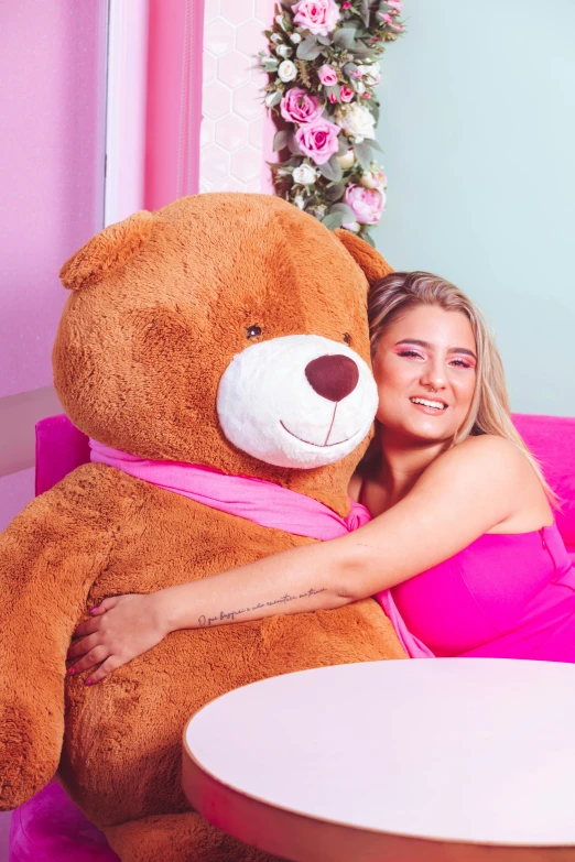 a smiling young woman hugs the face of a large teddy bear