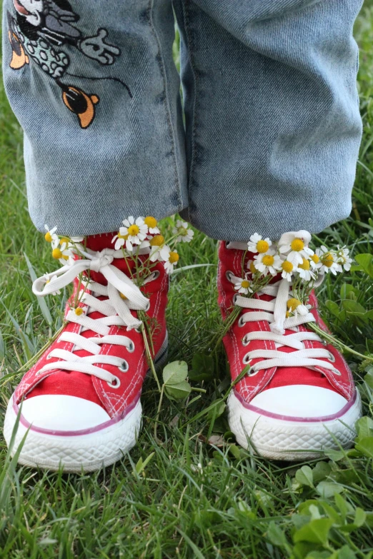 a child's red sneakers with daisies on the bottom of them