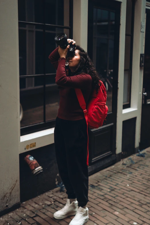 a woman with a camera and backpack looks through the lens