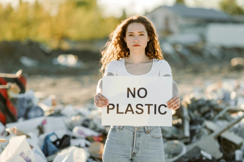 a woman holding a sign in front of garbage