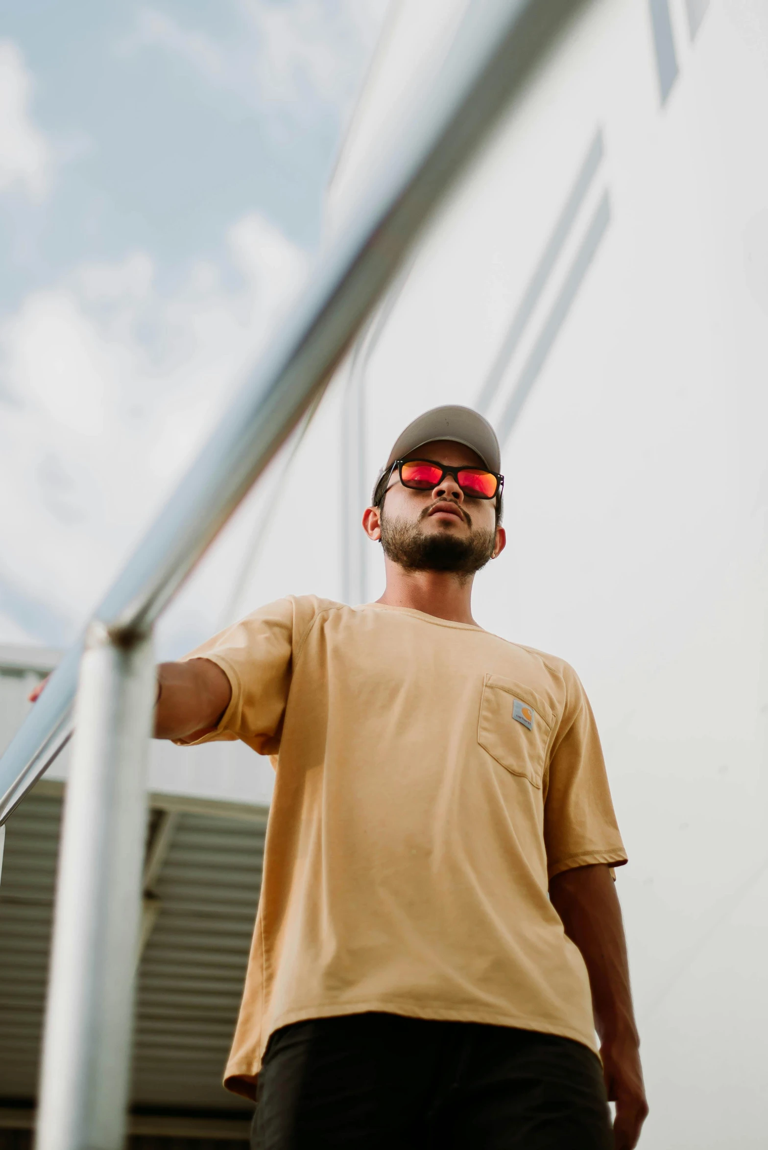 a man wearing a cap and sunglasses on the top of a balcony