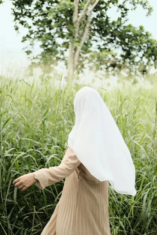 a woman in a white veil walking through a field