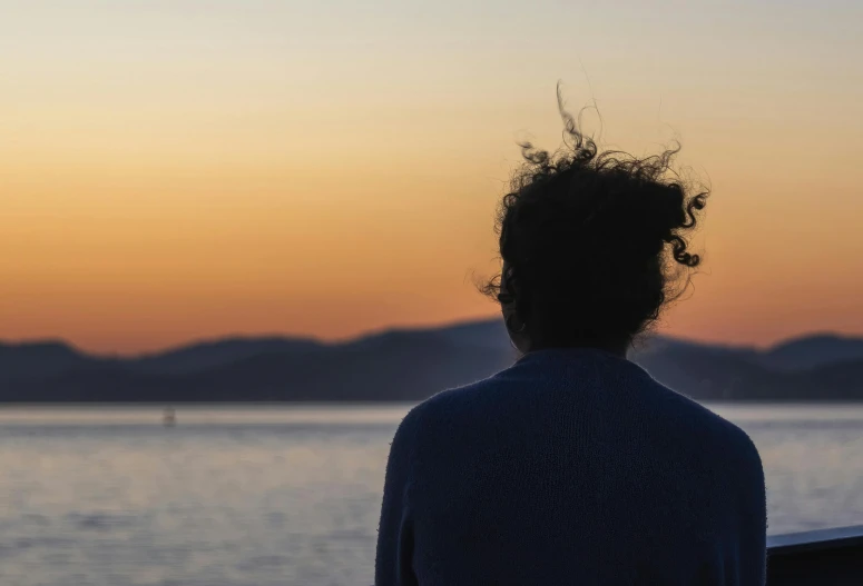 a man looking out at water with a beautiful sunset in the background