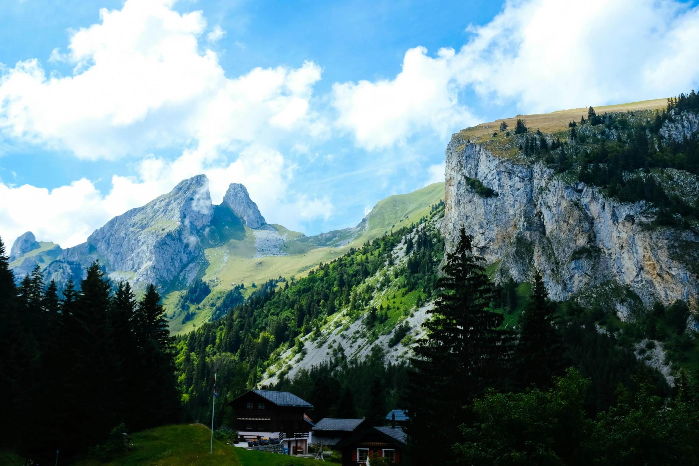 a mountainous mountain landscape with houses on the side and trees on the hillside